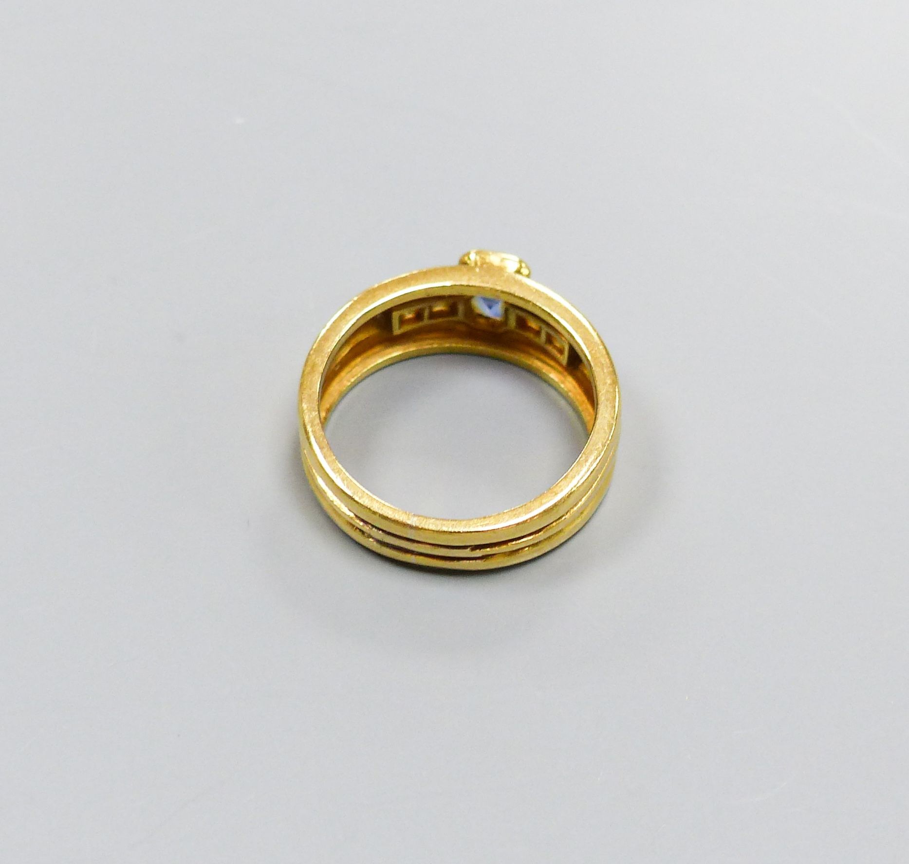 A modern 18ct gold, single stone sapphire and four stone diamond collet set dress ring, size M/N, gross 6.6 grams.